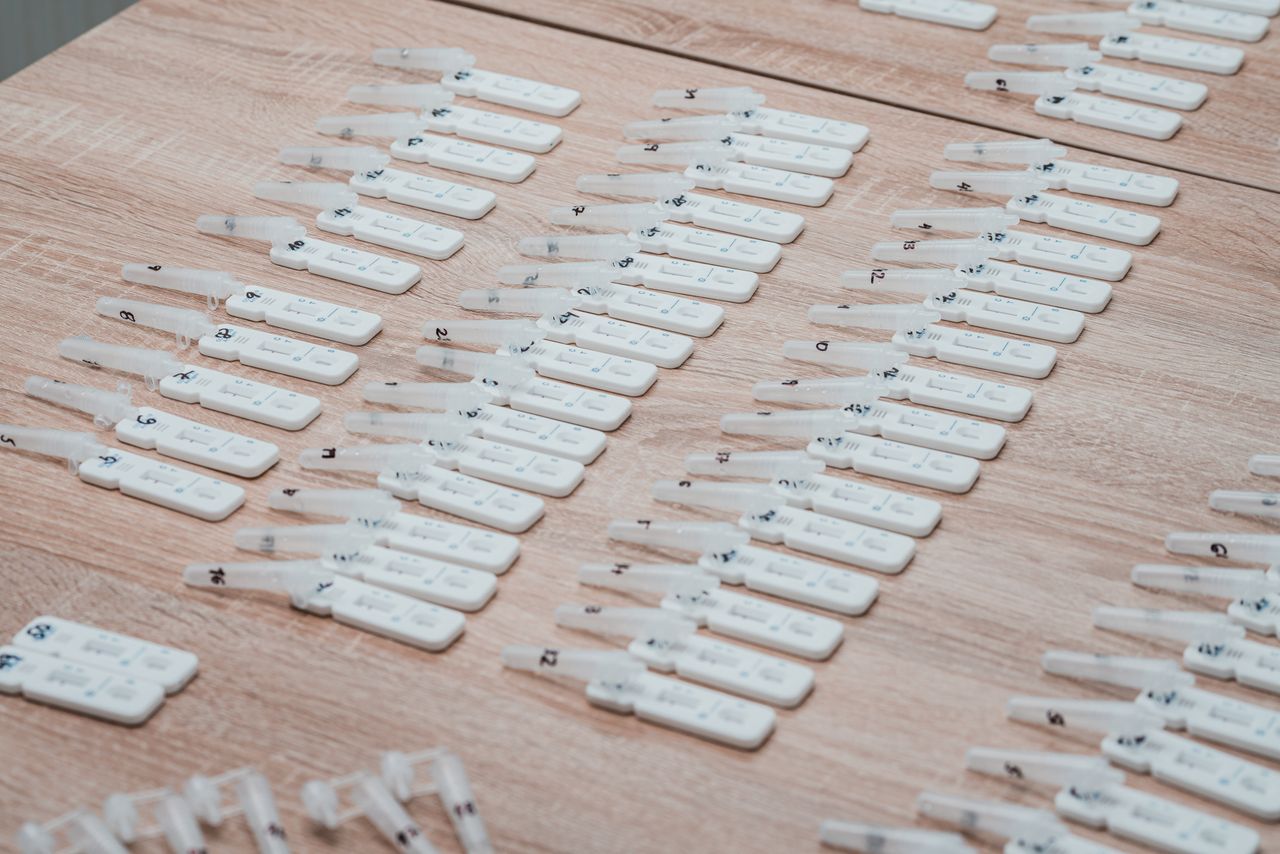 gallery-4 Multiple COVID-19 test kits displayed neatly on a wooden table indoors.