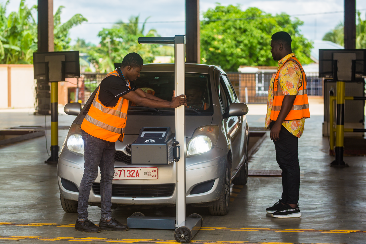 about-01 Two workers perform a detailed inspection on a car inside a garage, ensuring safety and compliance.