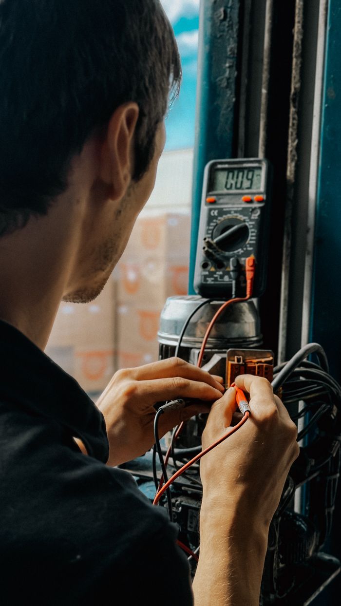 gallery-5 Electrician using a multimeter to check voltages in an industrial setting.