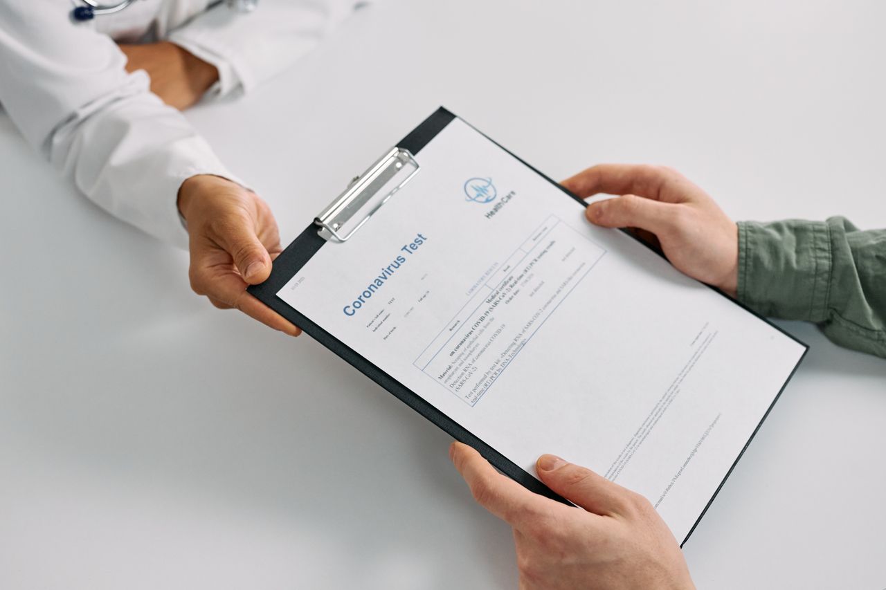 gallery-1 A doctor hands over coronavirus test results to a patient during a consultation in a medical clinic.