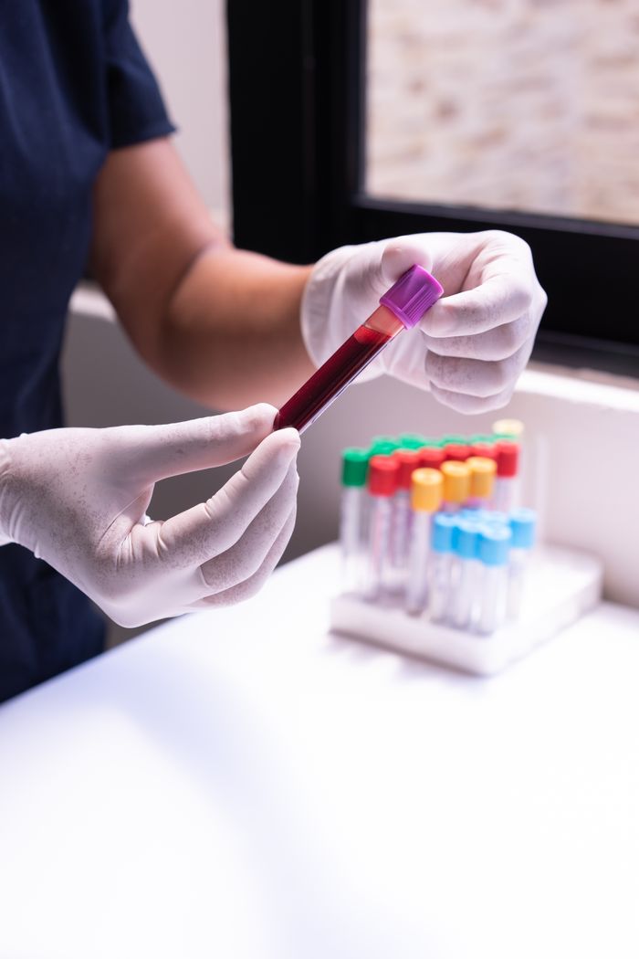 services-01 A healthcare worker examines a blood sample in test tubes, emphasizing medical precision and care.